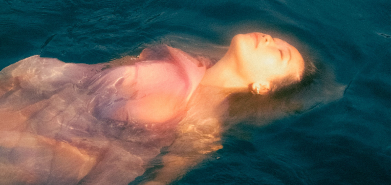 Artist Linying floats in a pool of water with a hazy filter as the artwork for her upcoming album